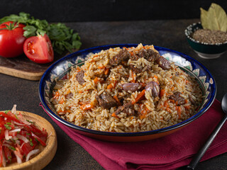 The concept of oriental cuisine. National Uzbek pilaf with meat in a cast-iron skillet, on a wooden table. background image. top view, copy space, flat lay