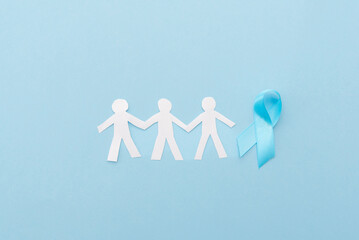 blue ribbon and paper men's silhouettes on blue background, prostate cancer awareness concept