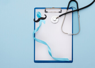 blue cancer prostate awareness ribbon with paper cut mustache and stethoscope on clipboard with...