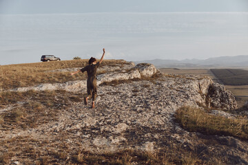 Freedom and adventure a person on top of a hill with arms outstretched and a distant car