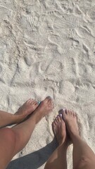 two women's feet on the beach. white sand beach. female feet on white sand beach background. summer.