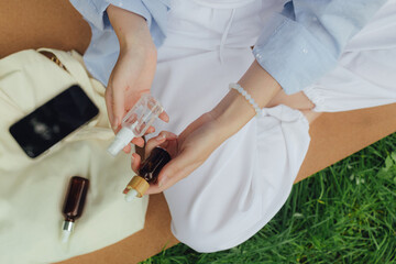 Close up of woman's hands with vial with essential oil in the park. Unity with nature and wellness concept. Part of the series. Concept of hair care product on hair ends or sun protection