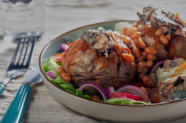 Jackets potatoes filled with baked beans and sardines with some salad.