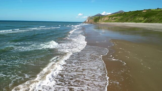 Nefyn beach fast drone low level sweep over waves breaking, beautiful North Wales coastline, UK