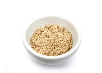 Shelled and ground almond nuts in a bowl. Edible, dried, brown seeds of Prunus dulcis. Ingredient in marzipan, nougat, cookies. Isolated macro food photo close up from above on white background.