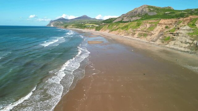 Nefyn beach fast drone high level sweep over waves breaking, beautiful North Wales coastline, UK