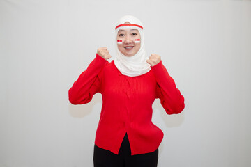 Woman in white hijab wearing red shirt. celebrating Indonesia's independence day. with clenched fists and excitement. isolation on white background.