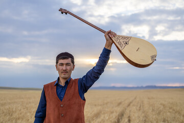 Kazakh, a man in Kazakh national dress playing dombra in the steppe. Kazakhstan. Central Asia....