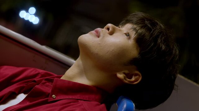 lonely sad asiatic male model close up while resting looking at the sky during night of summer 