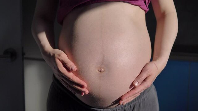 Heavily pregnant caucasian woman holds stomach