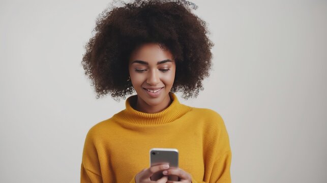 portrait beautiful smiling african american woman using smartphone, wearing yellow sweater isolated white background