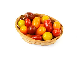 Different sorts of tomatoes in a woven basket isolated on white background.
