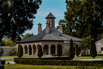 Historic building with arched entrances and a well-maintained garden in the foreground
