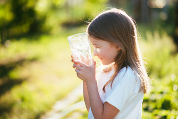 Cute child holding glasses of water in nature