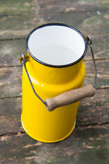 Yellow enamel retro milk churn on a wooden background