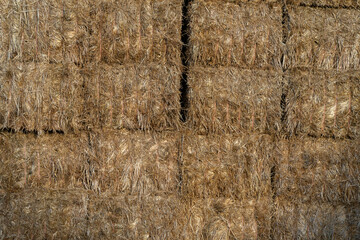 hay bales in a stack on a farm in australia in drought ready to feed to cows and sheep