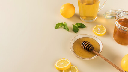 Honey with fresh lemons and fresh mint leaves on beige. Copy space