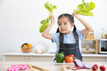 Fototapeta premium asian kid holding vegetables and preparing meal in the kitchen