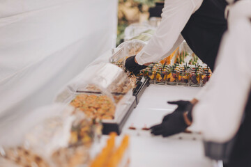 hands of a waiter prepare food for a buffet table in a restaurant. Catering.snacks on the table at the holiday. banquet, canapes. 