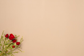 Beige background with red roses. Flat lay, top view. Copy space