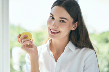 Dental Care And Nutrition. Woman Smiling Holding Green Apple, Promoting Dental Health Through Healthy Eating. Perfect Teeth 