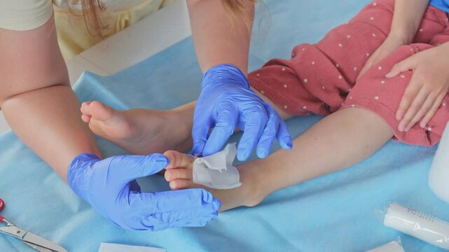 Registered Nurse Pediatritian Doctor Changing Medical Dressing on Foot Injury Wound during Treatment of Young Caucasian Girl Patient