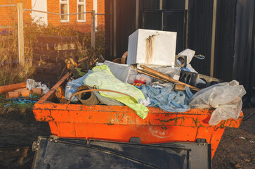 Full Orange Construction Debris Dumpster Outside Brick Building