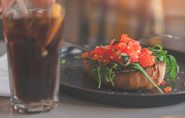 Close Up Of Tomato Bruschetta With  Glass Of Iced Tea On Table