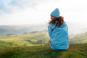 Woman Sitting on Hilltop With View of Rolling Green Hills