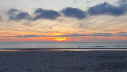 Walking on a beach at sunrise. Sand, sea and sky.
