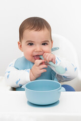 Cute Baby Boy Eating with Spoon and Bowl 