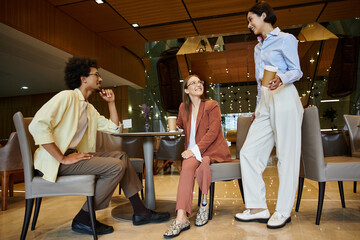 Multicultural colleagues enjoy a friendly conversation in a modern office setting.