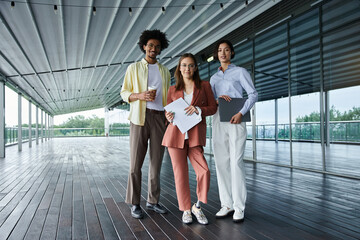 Three diverse colleagues chat and work on a rooftop terrace.