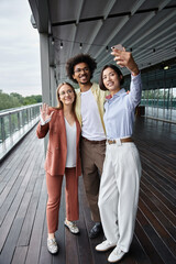 Obraz premium Three diverse coworkers enjoy a afternoon on a modern rooftop terrace, sharing laughs and taking a selfie.