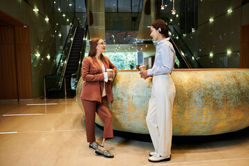 Two colleagues, one with a prosthetic leg, chat and enjoy coffee in a modern office lobby.