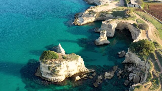 Stunning seascape with cliffs rocky arch and stacks (Faraglioni) at Torre Sant Andrea, Salento coast, Puglia region, Italy. Beautiful cliffs and sea stacks of Sant'Andrea, Salento, Apulia, Italy