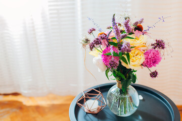 Close up of fresh summer bouquet put in vase on table. Pink, yellow, purple blooms. Floral arrangement at home