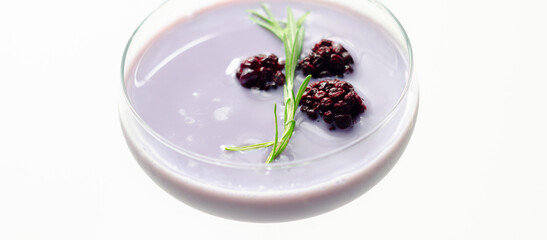 A glass of purple liquid with blackberries floating on top