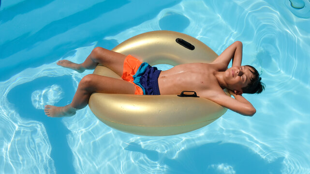 Young people relaxing in the pool on a hot day during the summer heat wave on top of a float