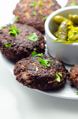 A plate of minced cutlets with a side of pickles