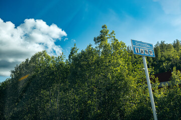 A blue road sign indicating a camping spot with green forest and blue skies in the background