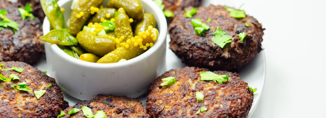 A plate of minced cutlets with a side of pickles