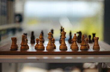A closeup of a chess board with the white pieces in focus in the foreground