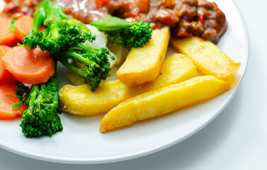 A plate of food with meat, french fries, and vegetables