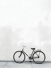 Obraz premium Minimalist black bicycle leaning against a white wall, showcasing simple yet elegant design against a clean background.