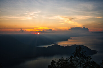 This captivating photo captures a golden sunrise over Lake Toba in Sumatra, Indonesia. The serene waters and lush hills create a tranquil scene, perfect for nature and travel enthusiasts seeking a bre