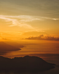 This captivating photo captures a golden sunrise over Lake Toba in Sumatra, Indonesia. The serene waters and lush hills create a tranquil scene, perfect for nature and travel enthusiasts seeking a bre