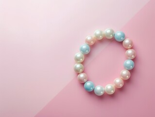 Obraz premium A pearl bracelet with pastel pink, blue and white pearls, lying on a pastel pink and light pink background.
