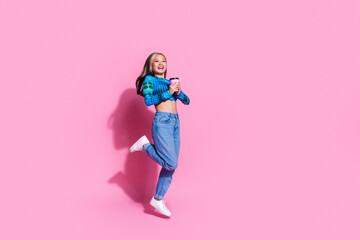 Full length photo of charming positive woman wear blue top jumping high drinking cacao empty space isolated pink color background