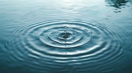 A serene photo capturing the moment a water droplet creates ripples on a calm surface, perfect for tranquility and nature themes.